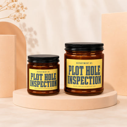 Two amber glass candles with black lids, labeled 'Plot Hole Inspection'.