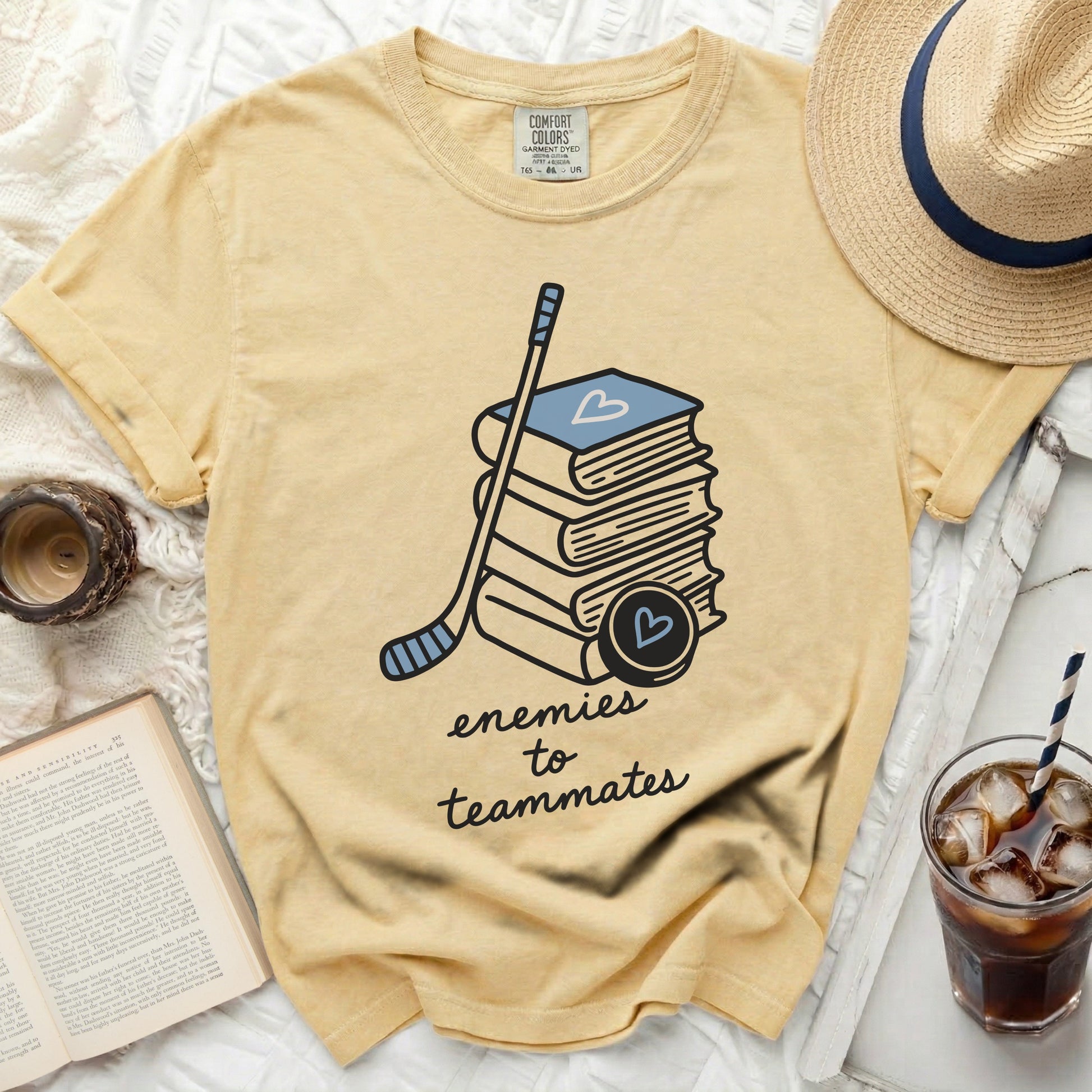Yellow t-shirt with stacked books, hockey stick, and heart puck.