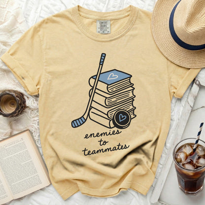 Yellow t-shirt with stacked books, hockey stick, and heart puck.