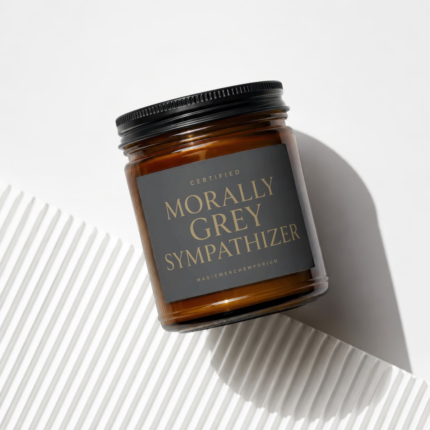 Amber jar candle with black lid reads "CERTIFIED MORALLY GREY SYMPATHIZER".