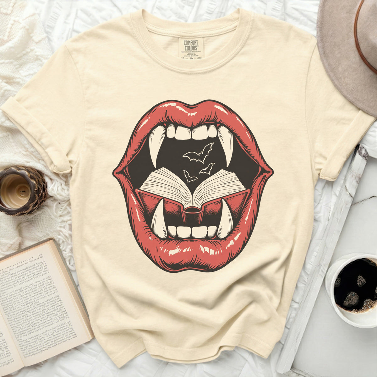 Vampire lips with fangs biting an open book with bats.