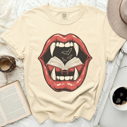 Vampire lips with fangs biting an open book with bats.
