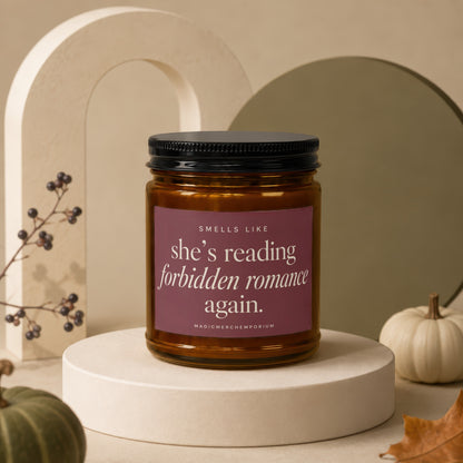 Amber jar candle with "she's reading forbidden romance again." text on maroon label.