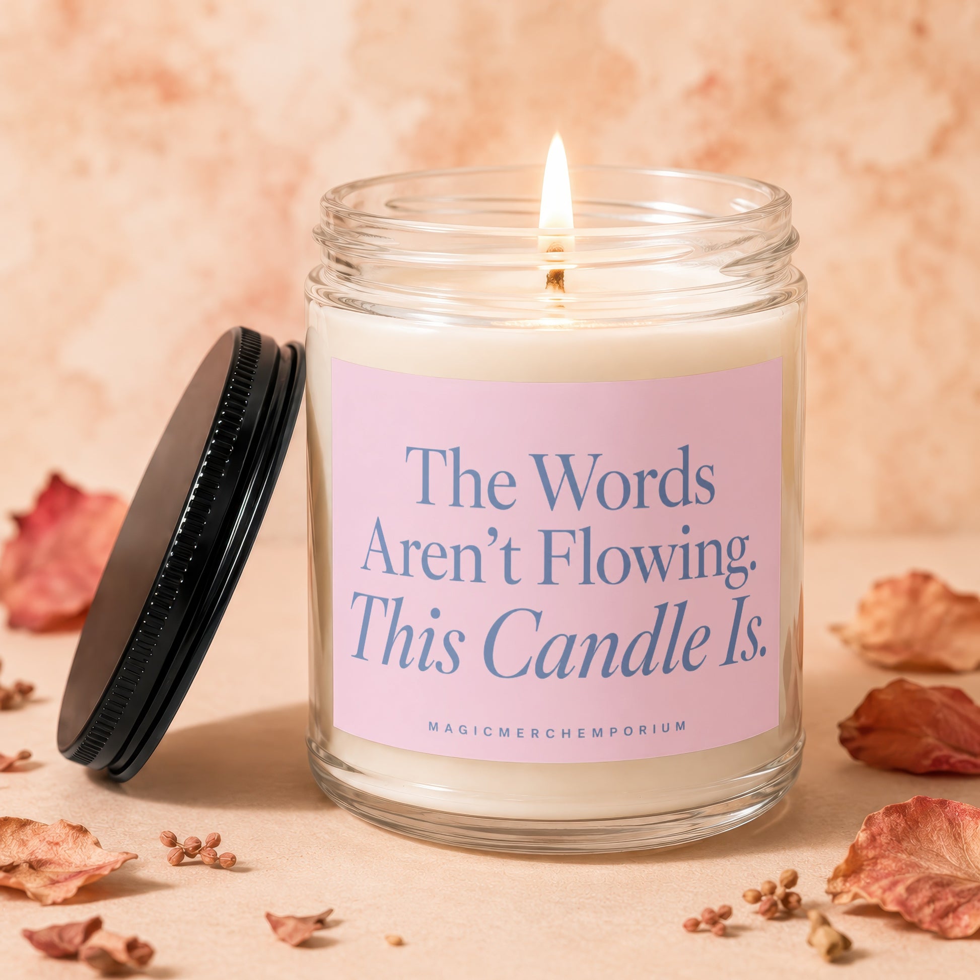 Candle with lit wick and label "The Words Aren't Flowing. This Candle Is."