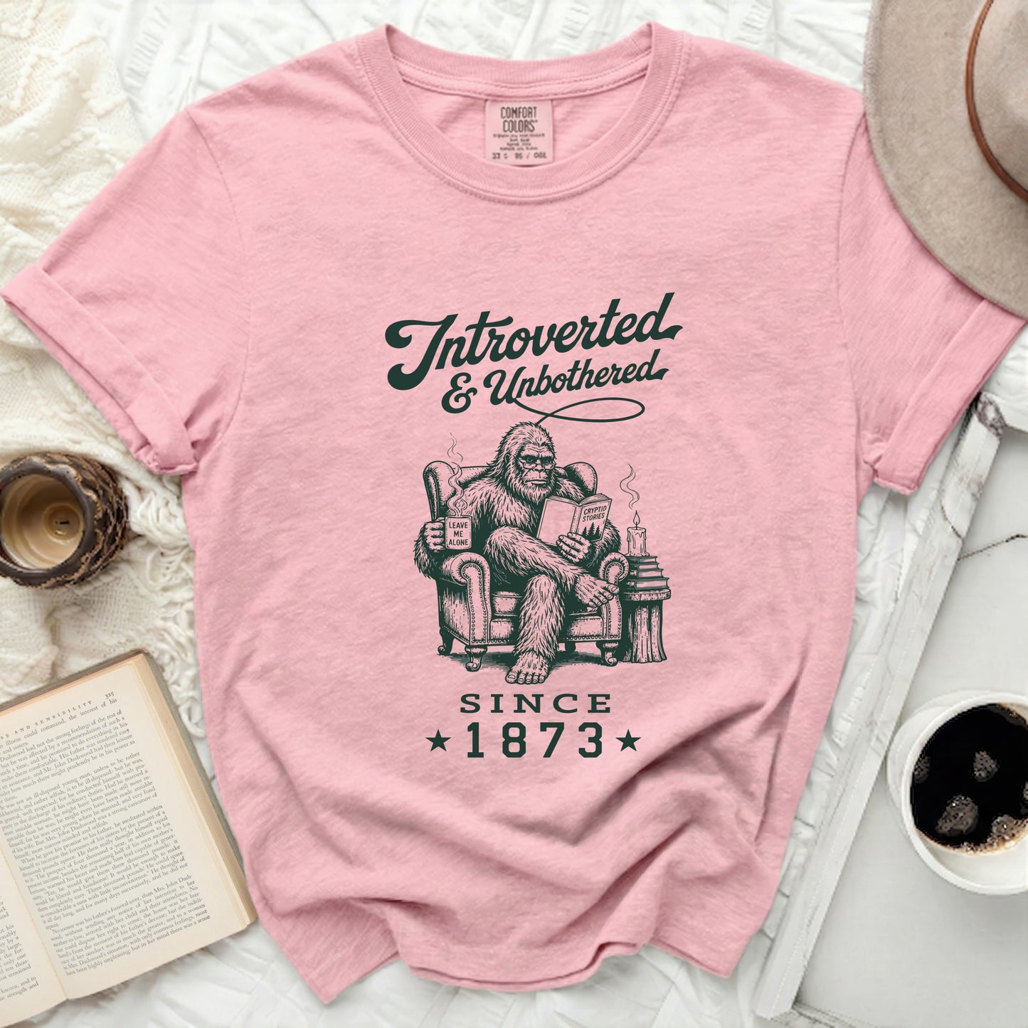 Pink t-shirt with Bigfoot reading and "Introverted & Unbothered Since 1873" graphic.