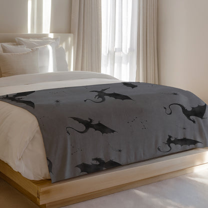 Grey blanket with a repeating pattern of black dragons and constellations.