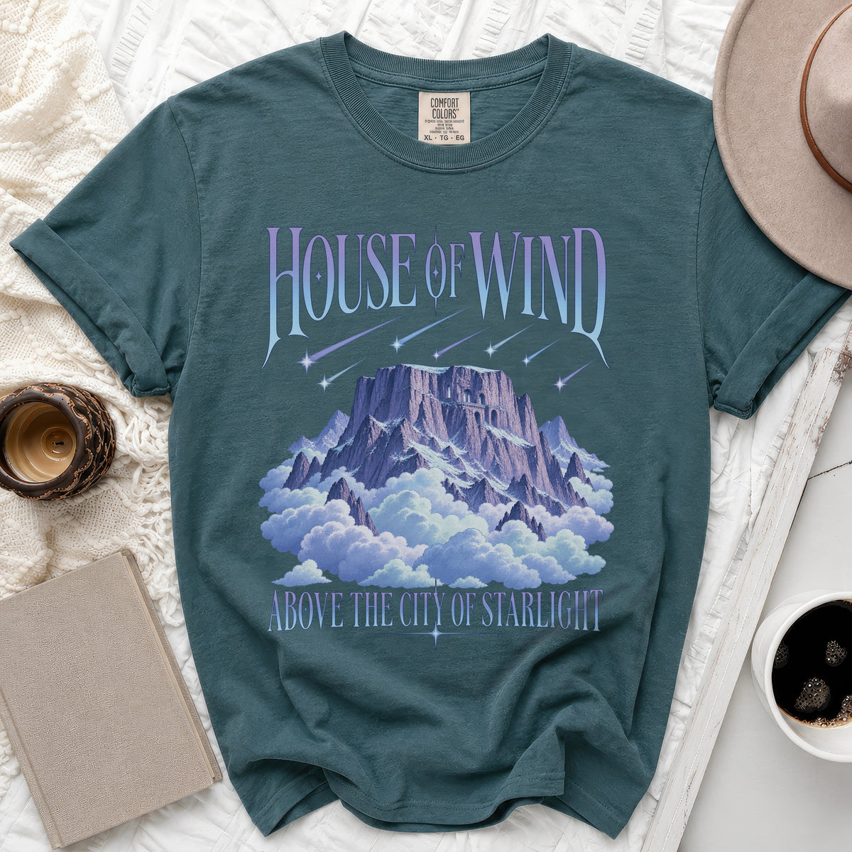 Teal t-shirt with "House of Wind Above the City of Starlight" graphic.