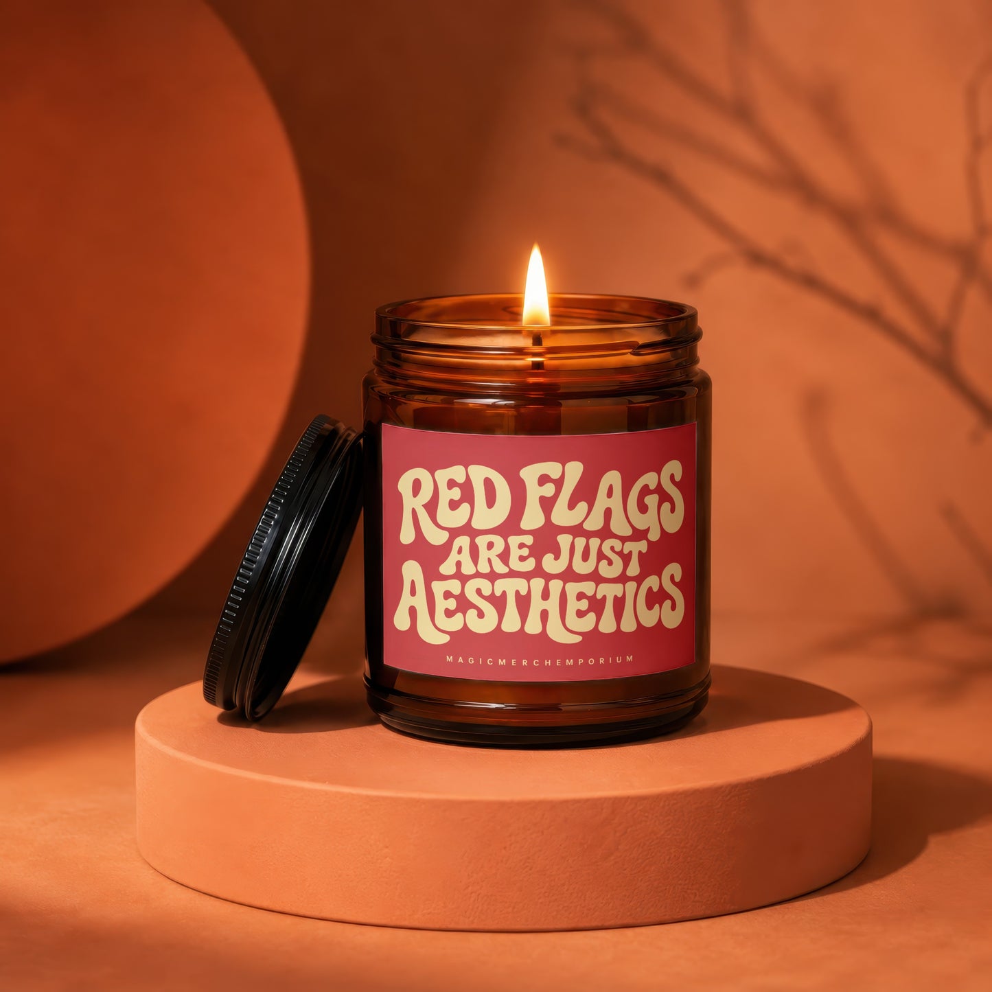 Amber jar candle with lit wick, reading "Red Flags Are Just Aesthetics".