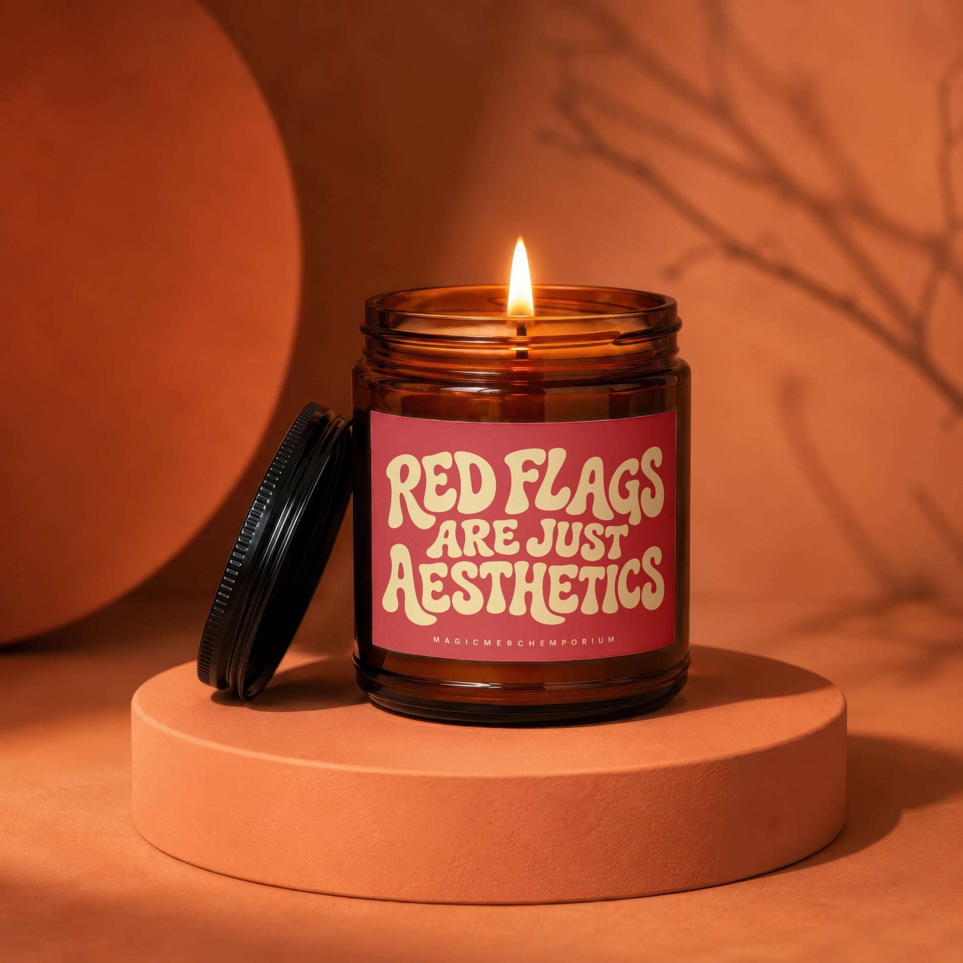 Amber jar candle with lit wick, reading "Red Flags Are Just Aesthetics".