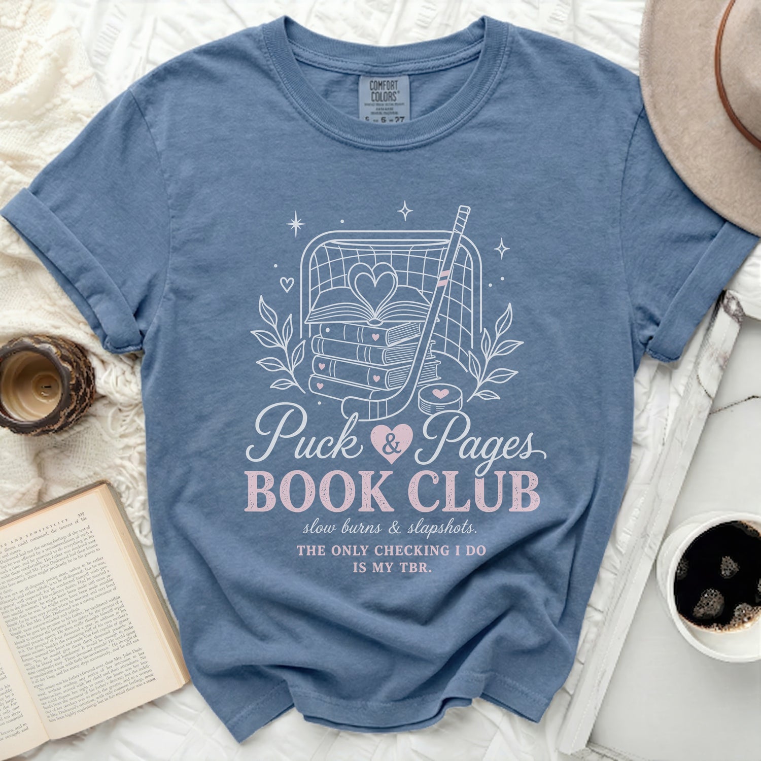 Blue t-shirt with "Puck & Pages Book Club" text and hockey imagery.