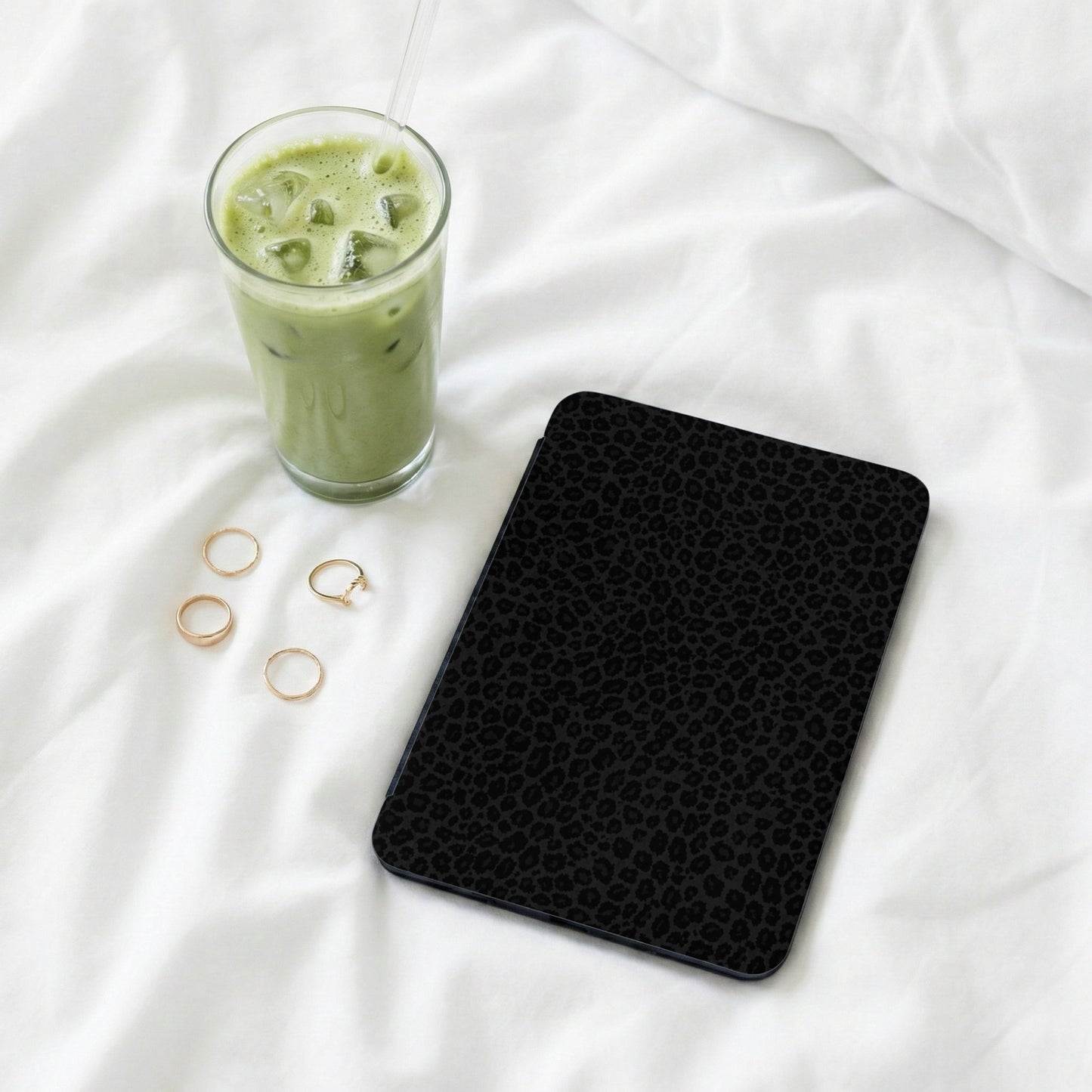 Black leopard print tablet case next to a glass of iced matcha and gold rings.