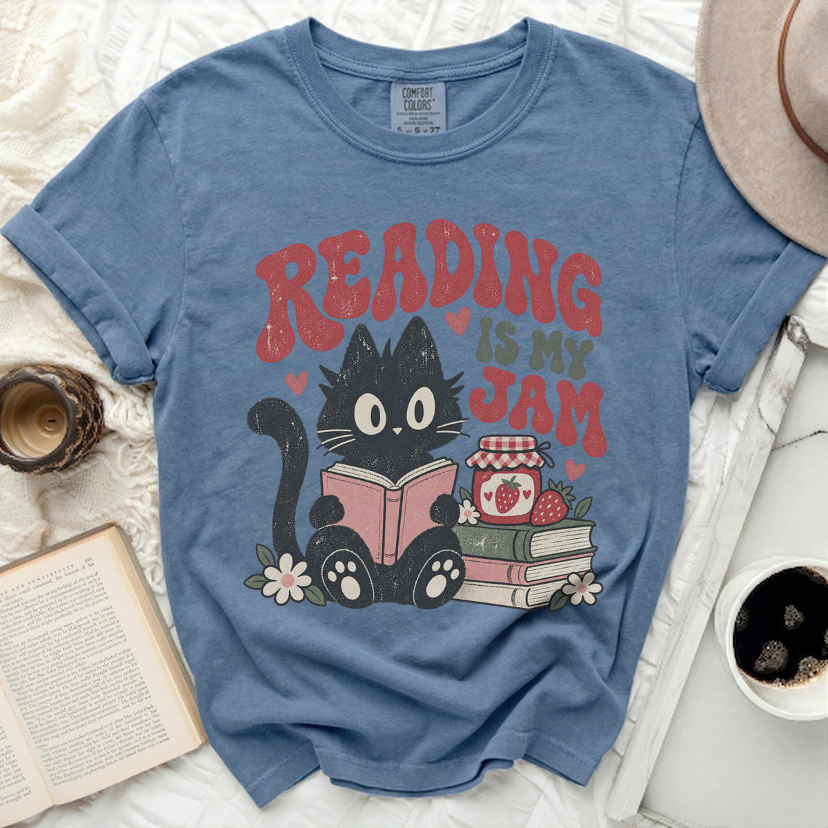 Black cat reads a book with "Reading is my Jam" text and strawberries.