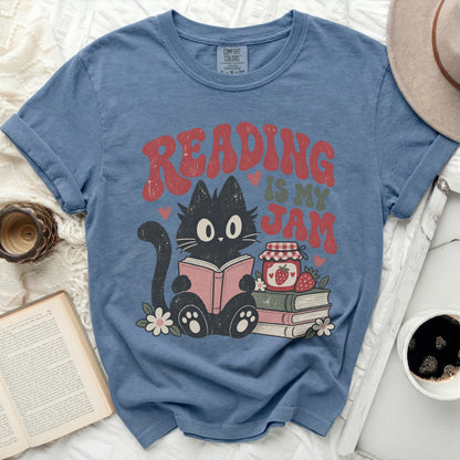 Black cat reads a book with "Reading is my Jam" text and strawberries.