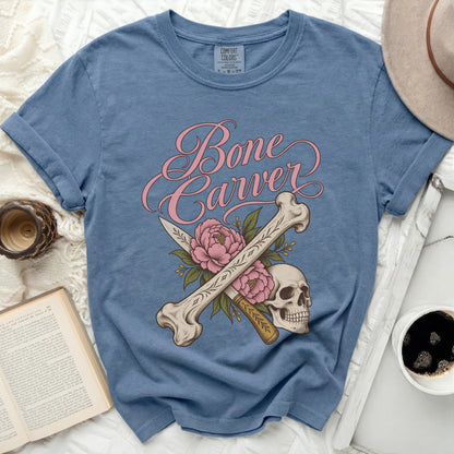 Blue t-shirt with "Bone Carver" text, crossed bones, skull, knife, and pink flowers.