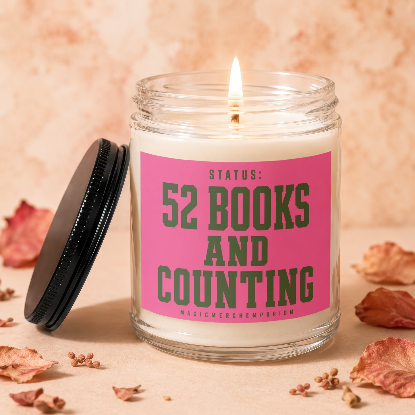 Glass candle with pink label reading "STATUS: 52 BOOKS AND COUNTING"