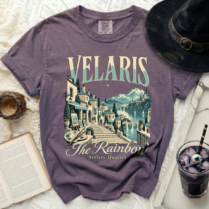 Purple t-shirt with "Velaris The Rainbow Artists' Quarter" graphic depicting a scenic town.