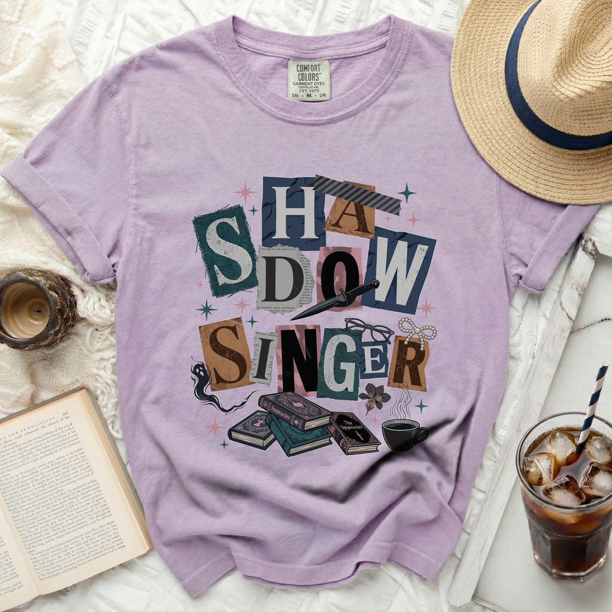 Lavender t-shirt with "Shadow Singer" text collage and book illustrations.