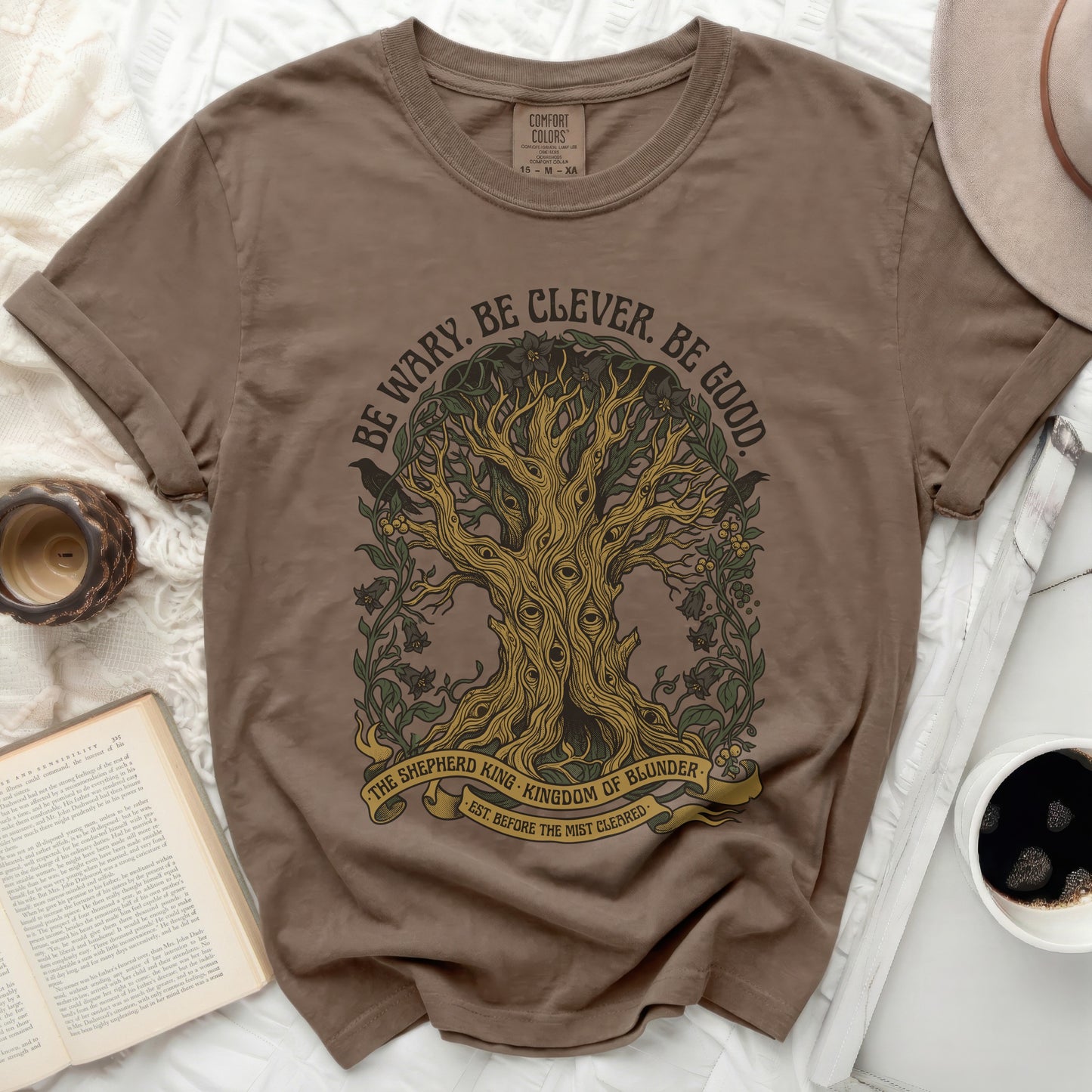 Brown t-shirt with tree graphic and "Be Wary. Be Clever. Be Good." text.