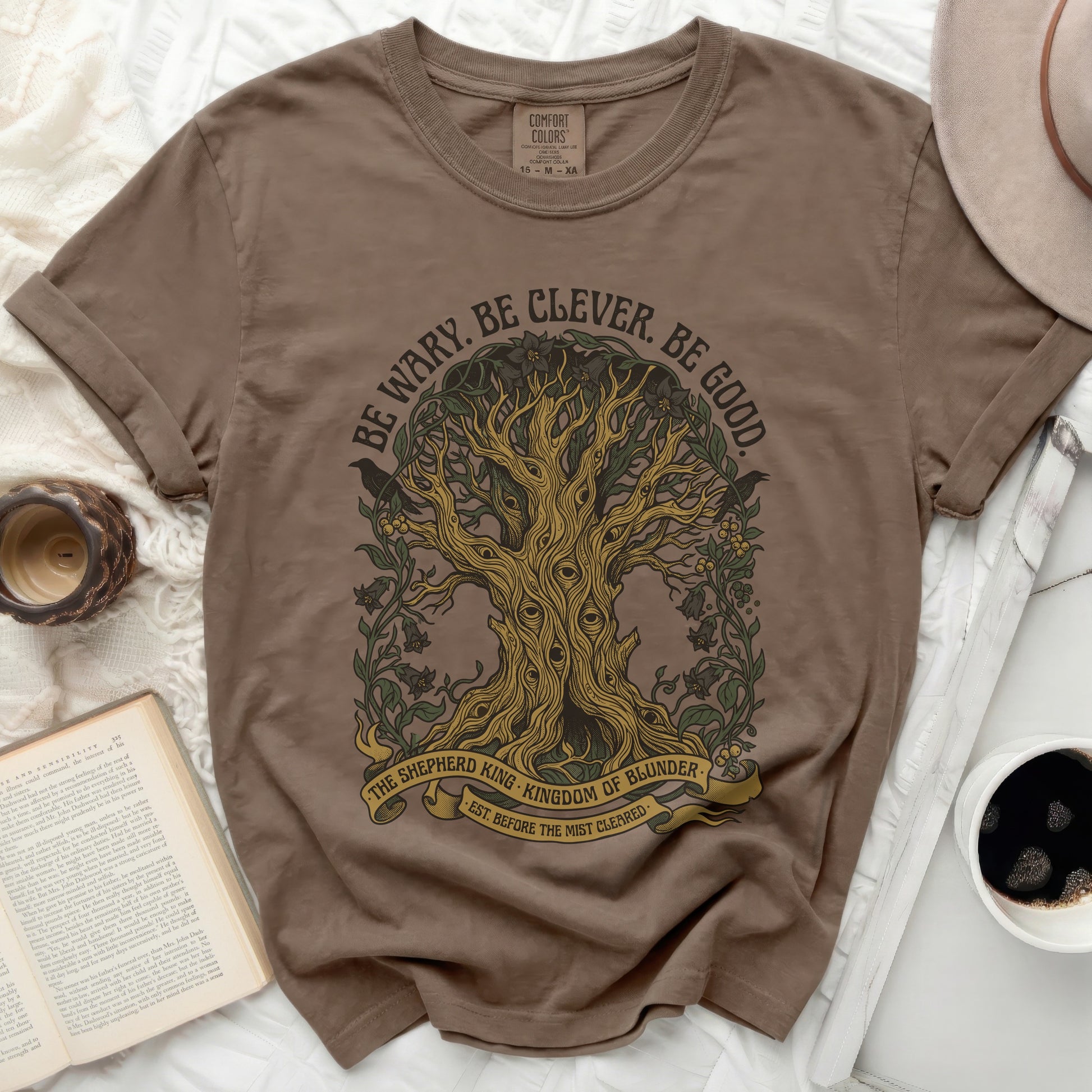 Brown t-shirt with tree graphic and "Be Wary. Be Clever. Be Good." text.