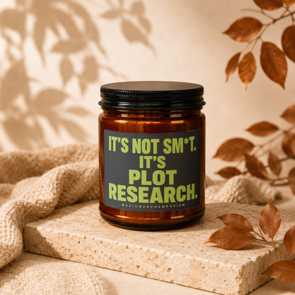 Amber jar candle with black lid, text reads "It's Not Sm*t. It's Plot Research."