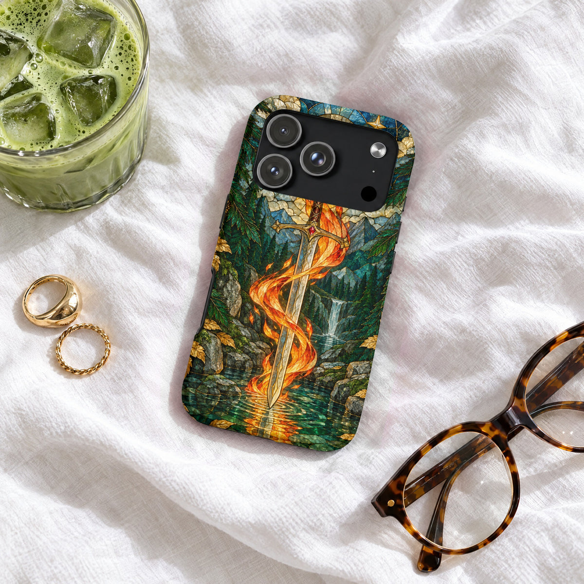 An iPhone case with a stained-glass design depicting a flaming sword, resting on a white fabric surface.