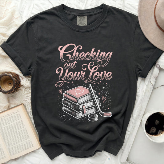 Black t-shirt with pink text "Checking Your Love" and stack of books.