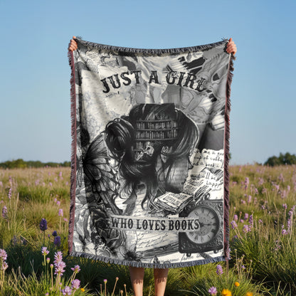 A person is holding up a blanket with a black and white image of a book and the text "Just a girl who loves books" against a field of purple flowers.