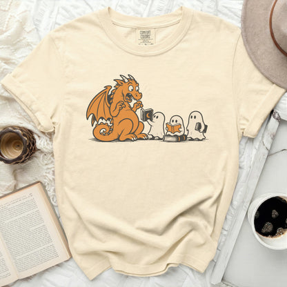 Orange dragon and ghosts reading books on a cream t-shirt.