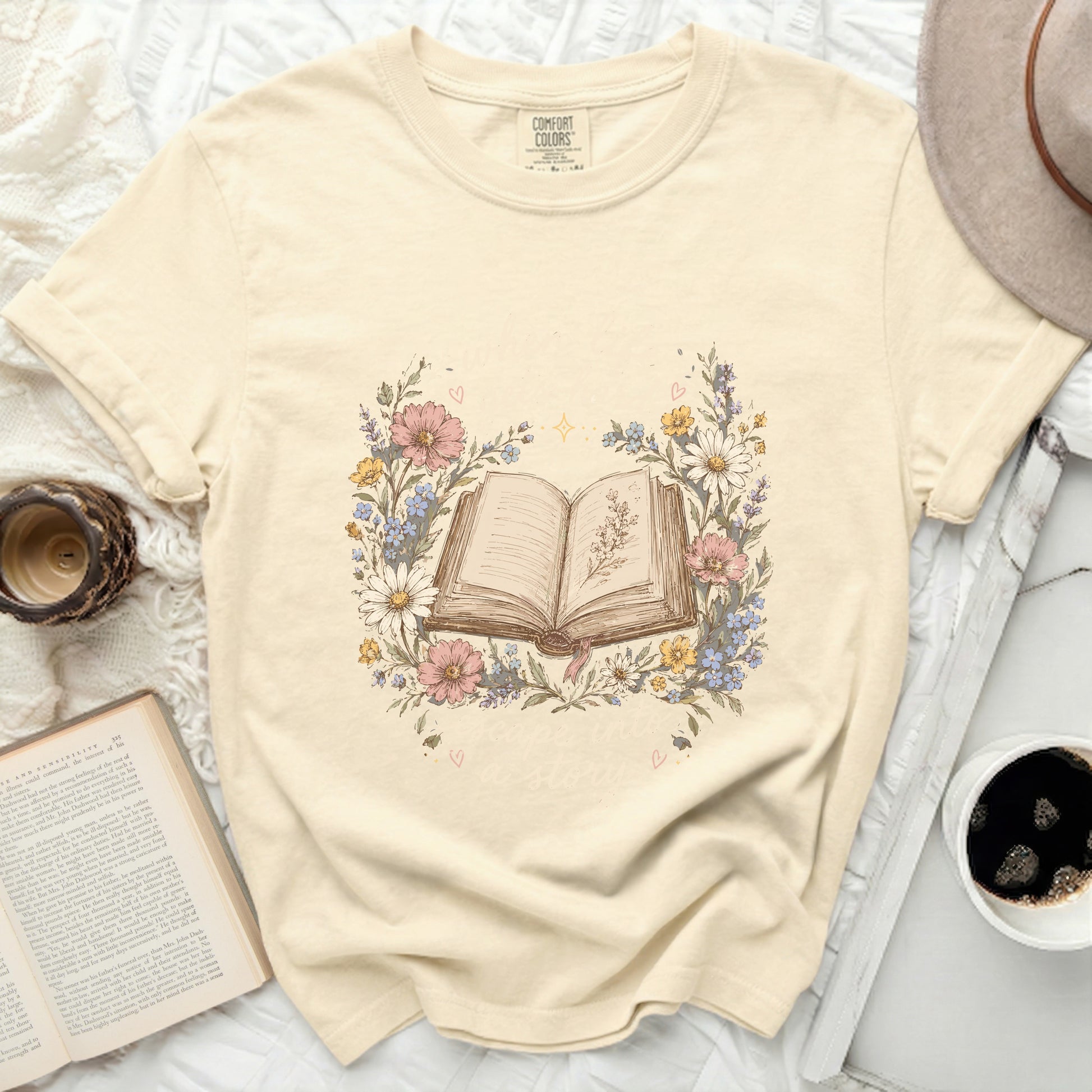 Cream t-shirt with an open book surrounded by flowers and the text "Read more stories".