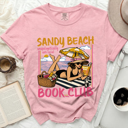 Pink t-shirt with woman reading on beach and "Sandy Beach Book Club" text.