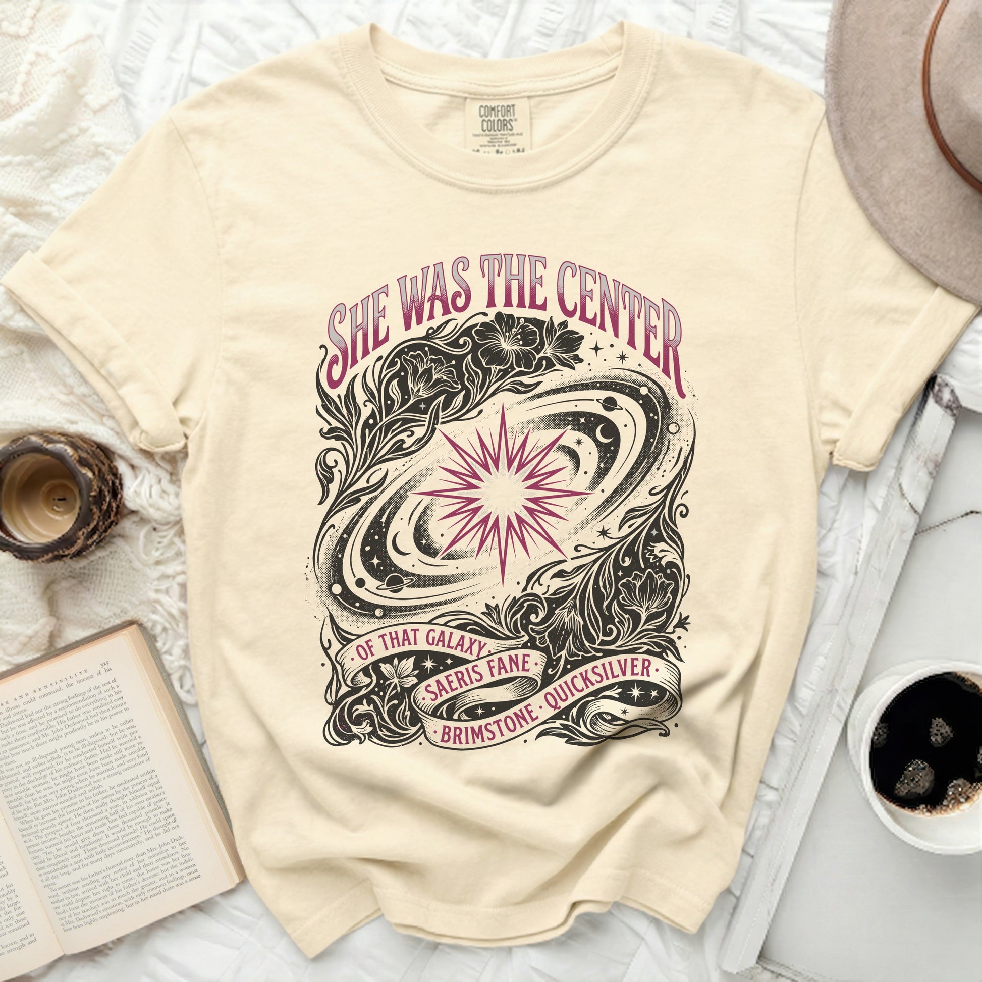 Cream t-shirt with "She was the center of that galaxy" starry design.