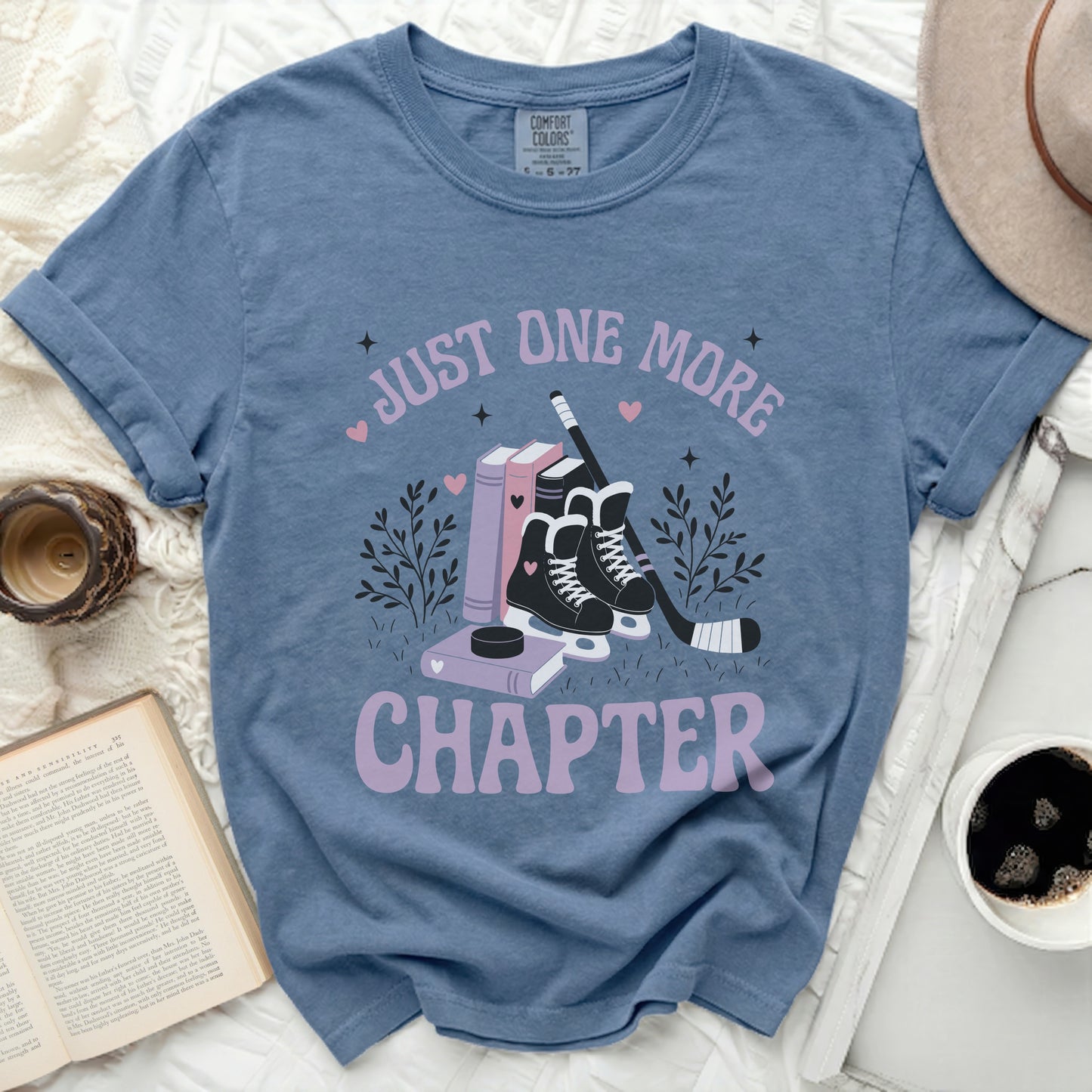 Blue t-shirt with "Just One More Chapter" text and hockey theme.