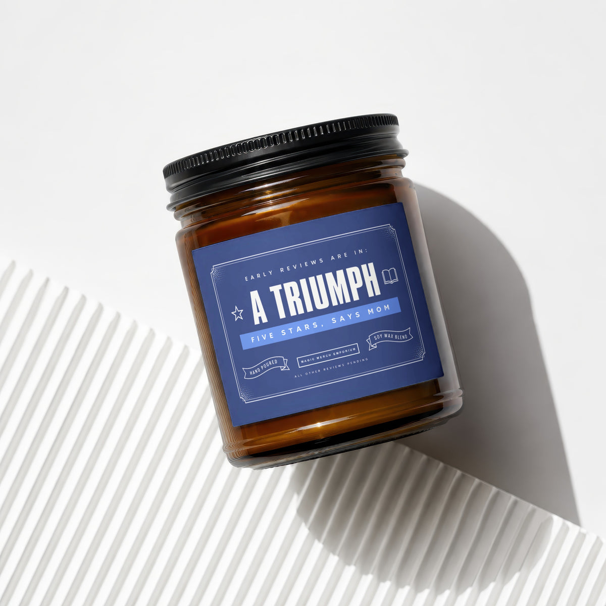 Amber jar candle labeled "A Triumph" with "Five Stars, Says Mom" and "Soy Wax Blend".