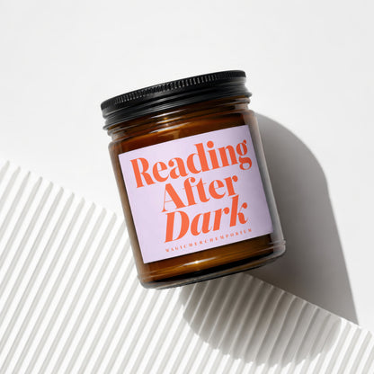 Amber jar candle with a lavender label reading "Reading After Dark" and "MagicMerchEmporium".