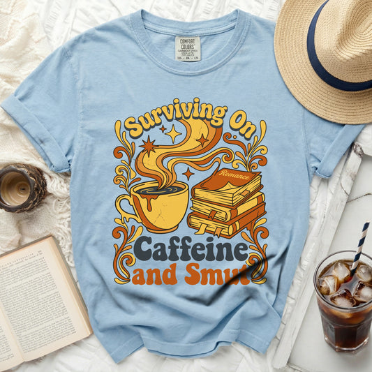 Light blue t-shirt with "Surviving On Caffeine and Smut" graphic.