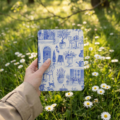 Hand holding a blue and white toile print item with a garden scene.
