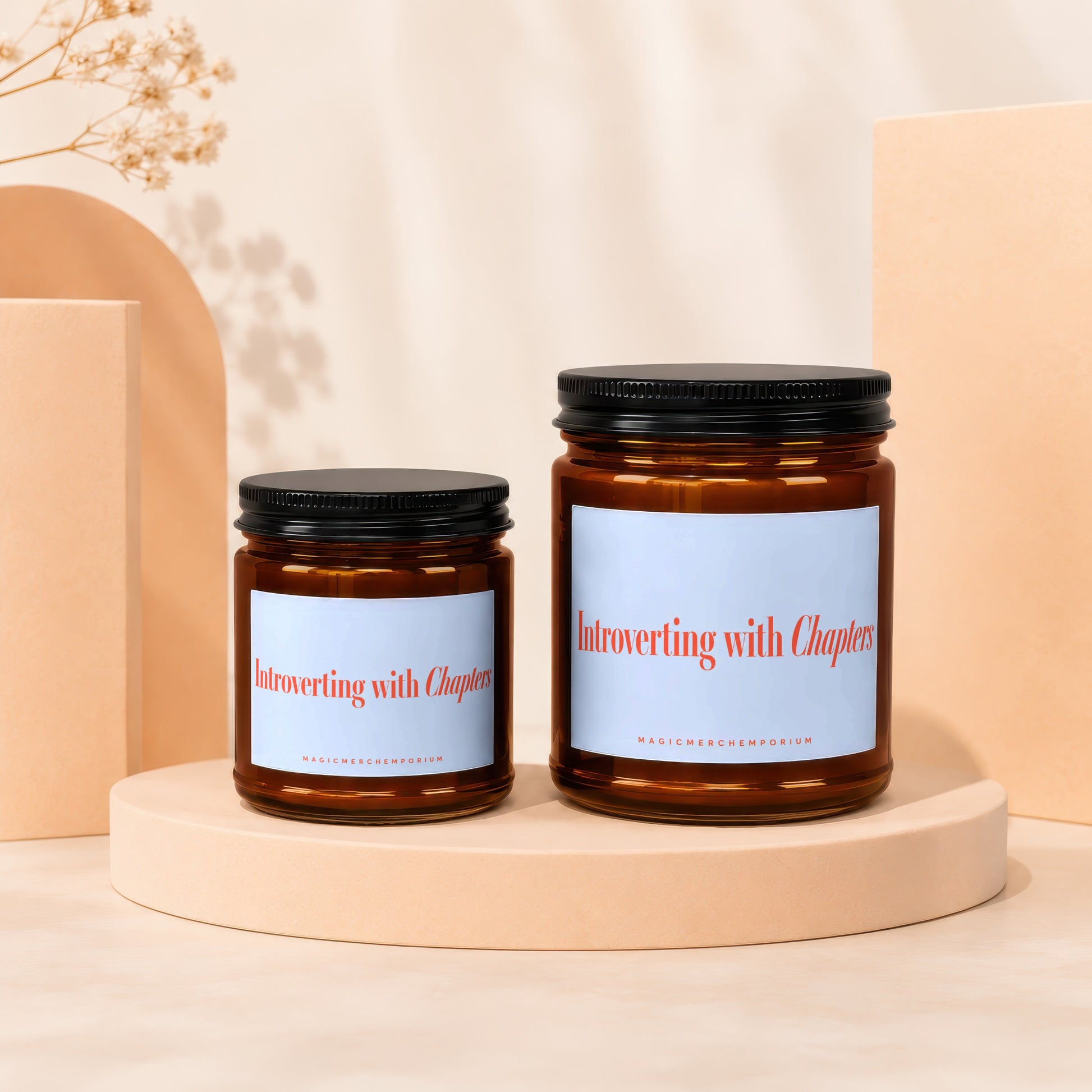 Two amber glass candles with black lids labeled "Introverting with Chapters".