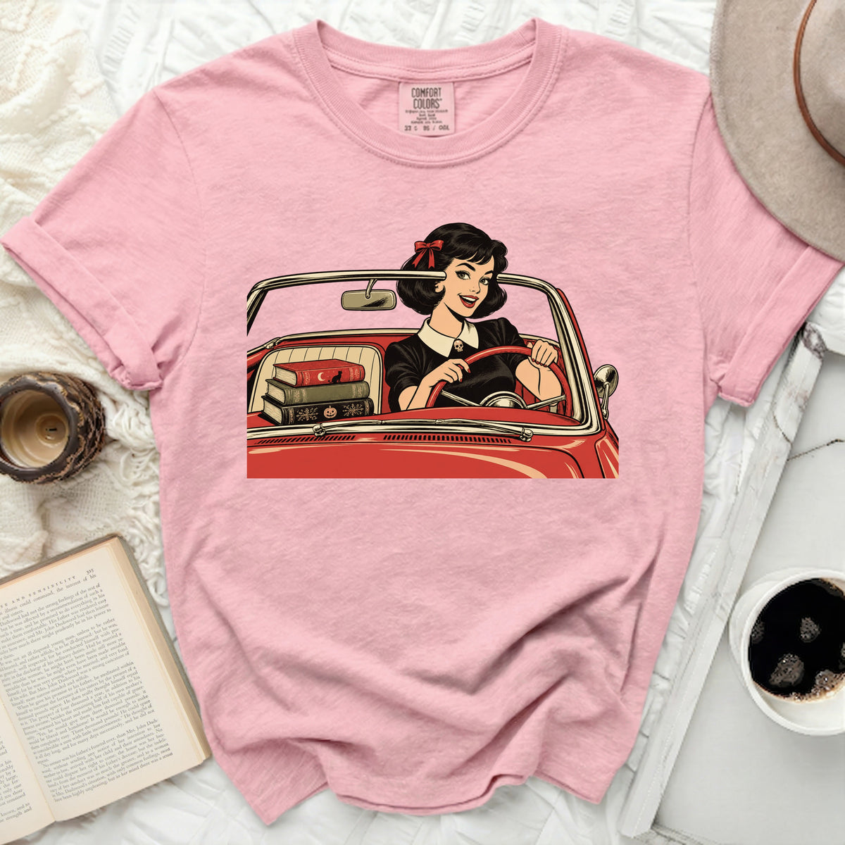 Pink Comfort Colors t-shirt with graphic of woman driving a red convertible with books.