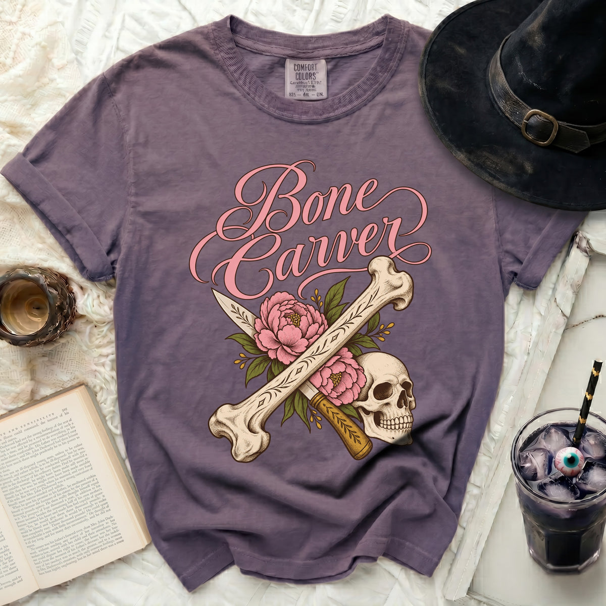 Purple t-shirt with "Bone Carver" text, skull, bones, knife, and flowers graphic.