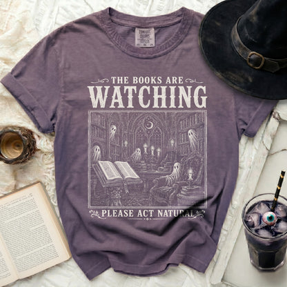 Purple t-shirt with "The Books Are Watching" and ghost library design.