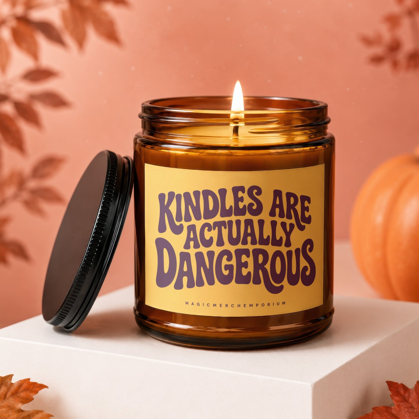 Amber jar candle with "KINDLES ARE ACTUALLY DANGEROUS" text and a lit flame.