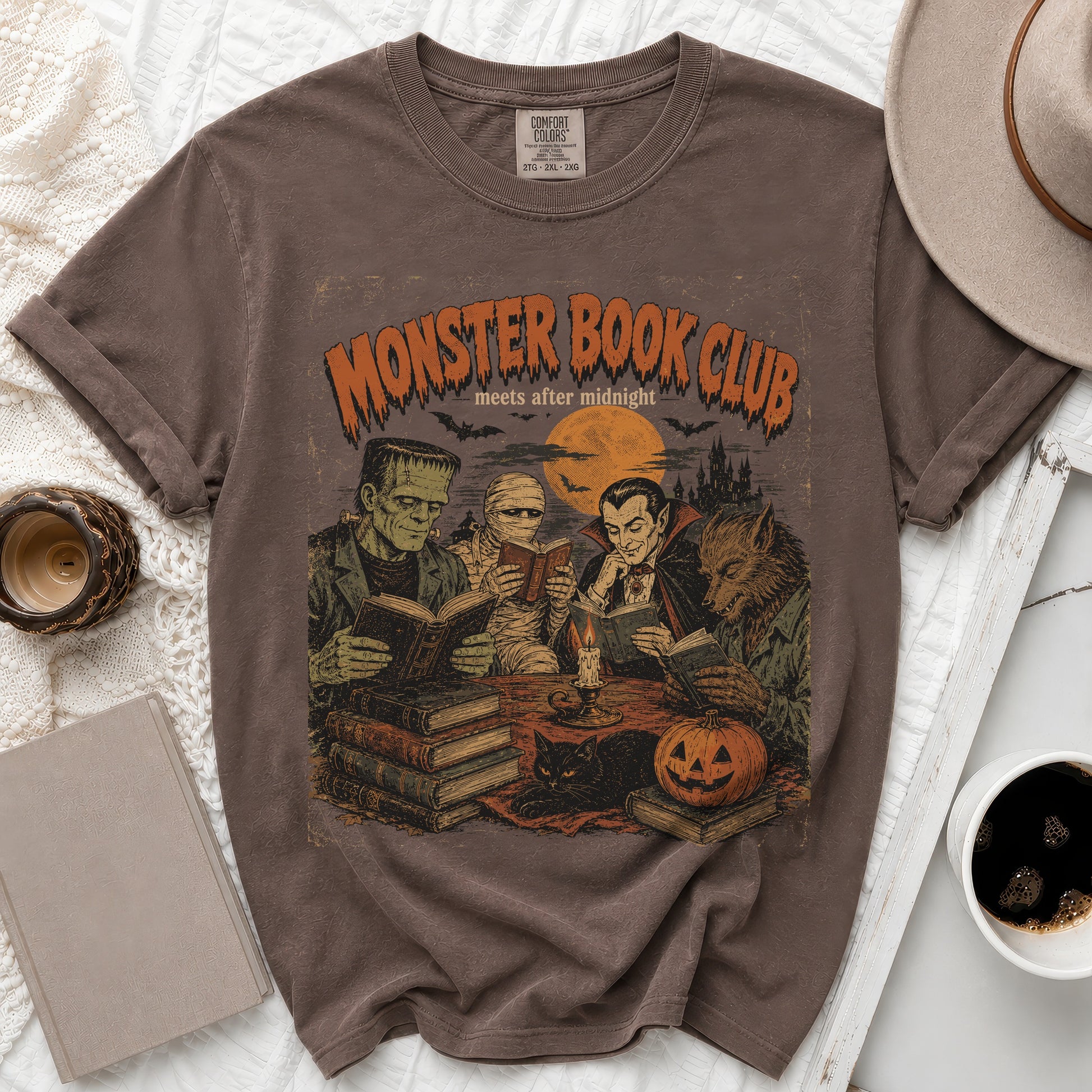 Brown t-shirt with screen print of classic monsters in a book club, with bats and moon.