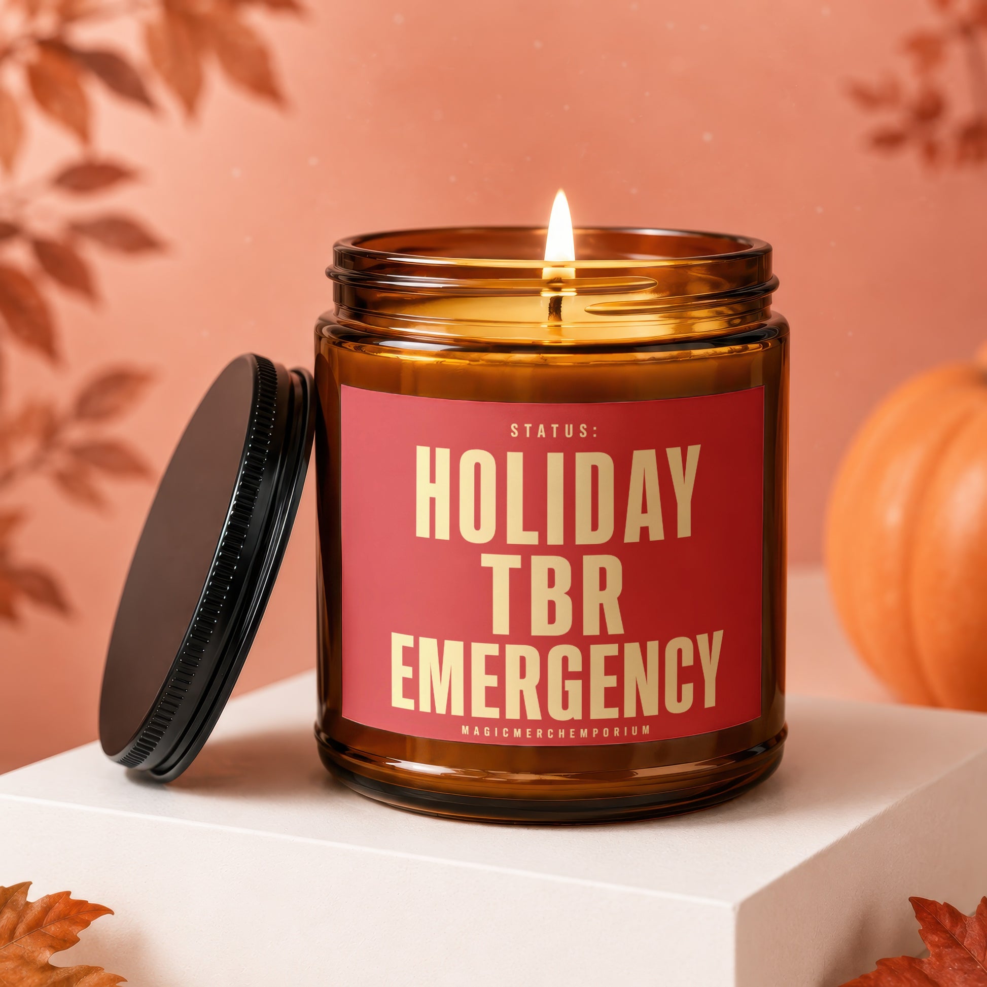 Lit amber glass candle with red label stating "HOLIDAY TBR EMERGENCY"