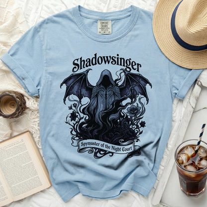 Light blue t-shirt with a dark graphic of a hooded figure with wings and text.