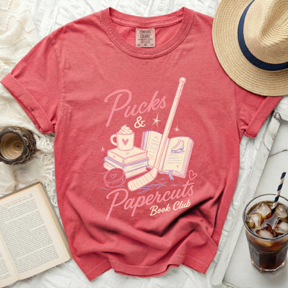 Coral t-shirt with "Pucks & Papercuts Book Club" graphic.