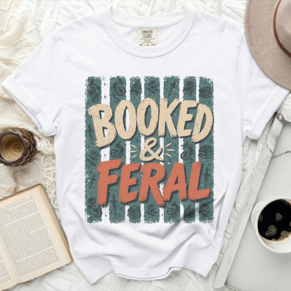 White t-shirt with "Booked & Feral" text and book-themed graphics.