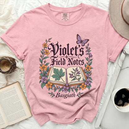 Pink t-shirt with "Violet's Field Notes Basgiath" text and floral design.