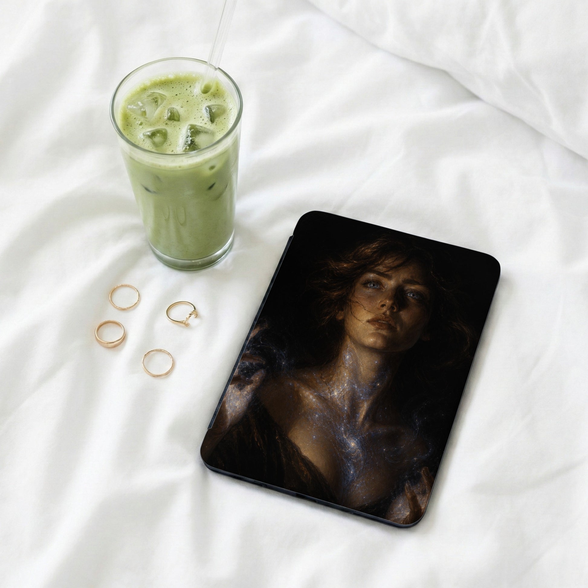Tablet featuring artwork of a sparkling, ethereal woman next to a green drink and rings.
