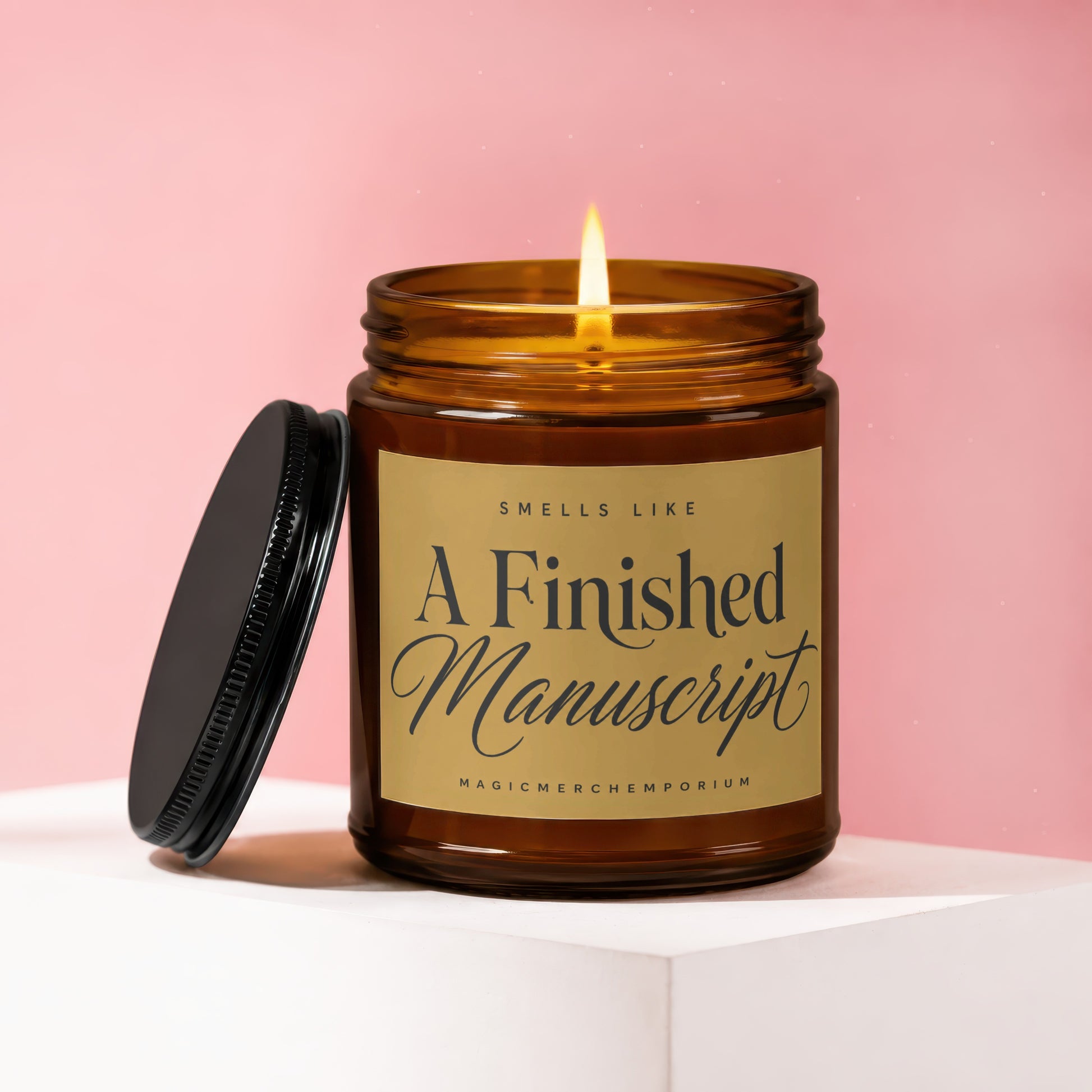 Amber candle with lit flame and black lid labeled "A Finished Manuscript."