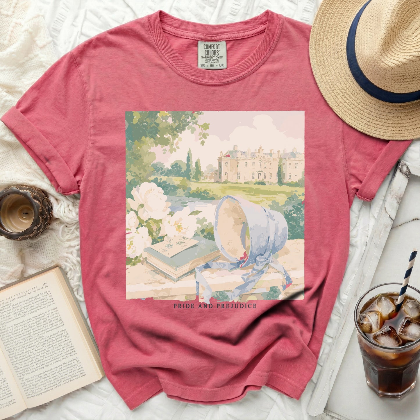 Pink t-shirt with a painting of a manor, books, and bonnet, "Pride and Prejudice" text.